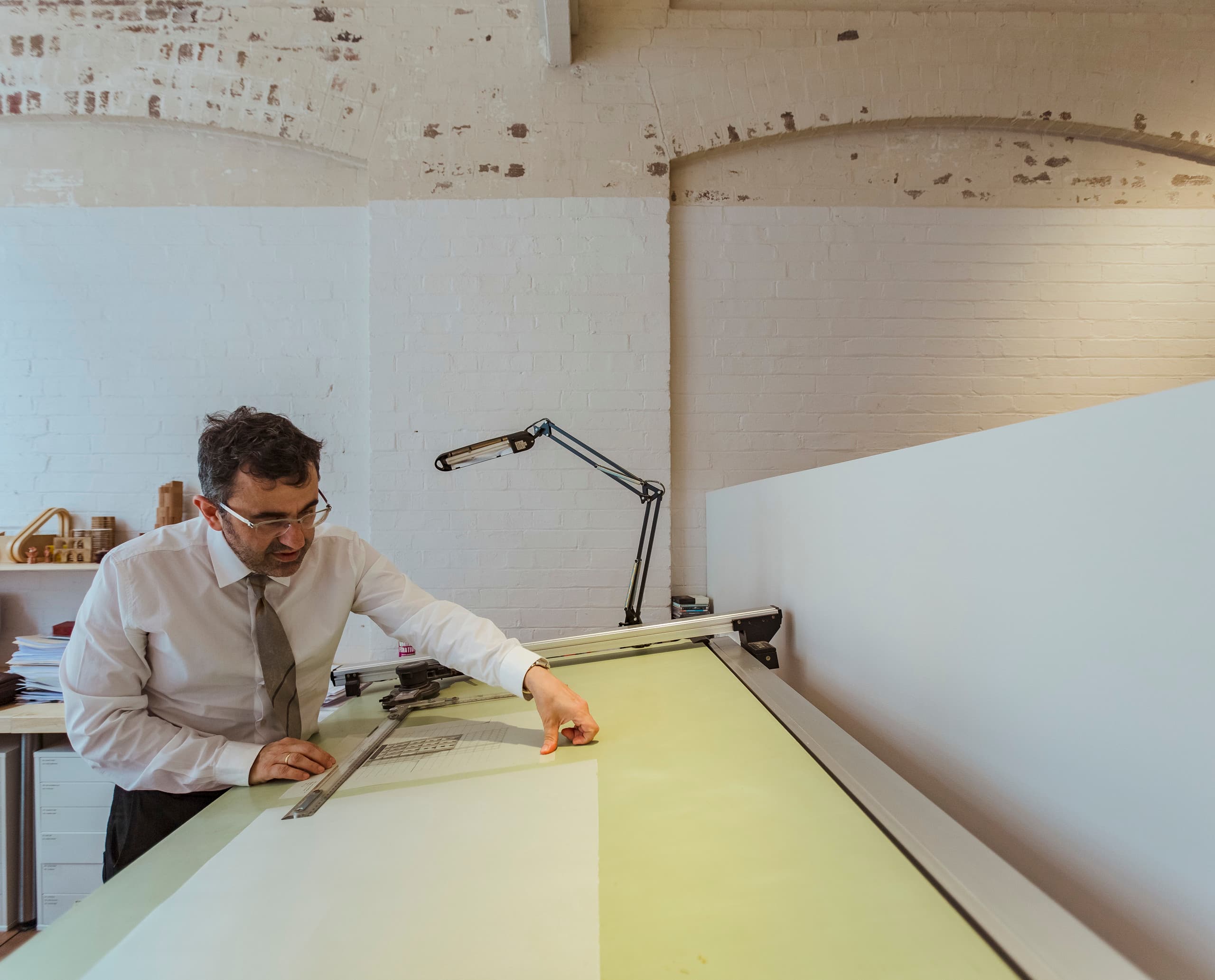 Architekt Angelo Candalepas am Zeichentisch in seinem Büro in Sydney, beleuchtet mit ERCO Licht.